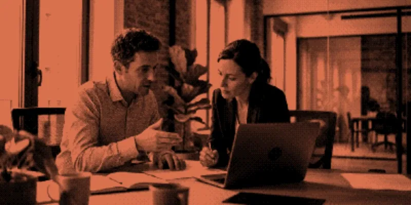 Two colleagues at a Madrid office desk reviewing a document together