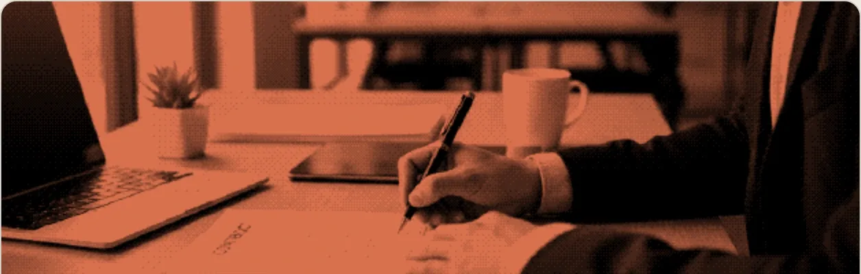 A new hire signing an offer at a desk beside an open laptop